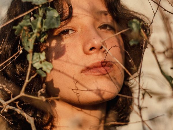 Person stretching gently outdoors with a calm expression, sun setting behind.